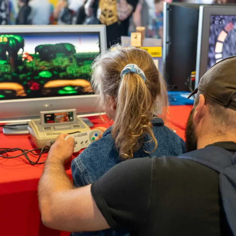 Famille jouant aux jeux vidéo rétro lors d'un festival Geek Life